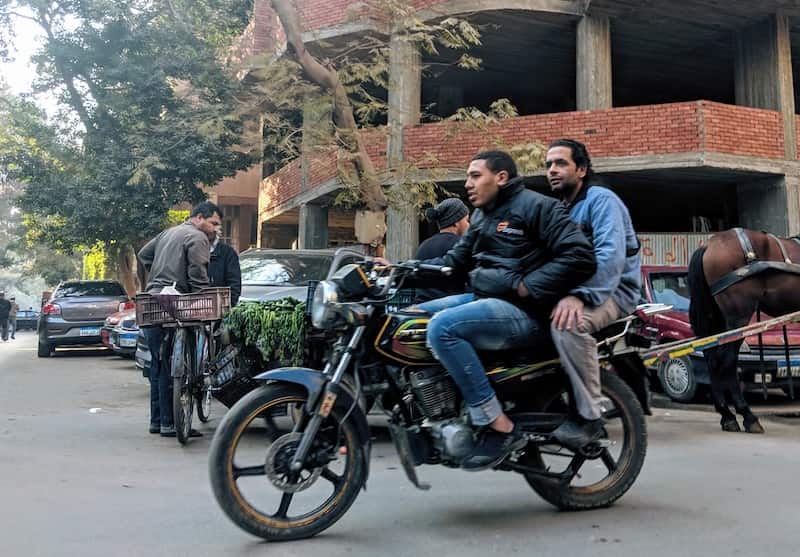 two men not wearing helmets and driving dangerously in cairo traffic