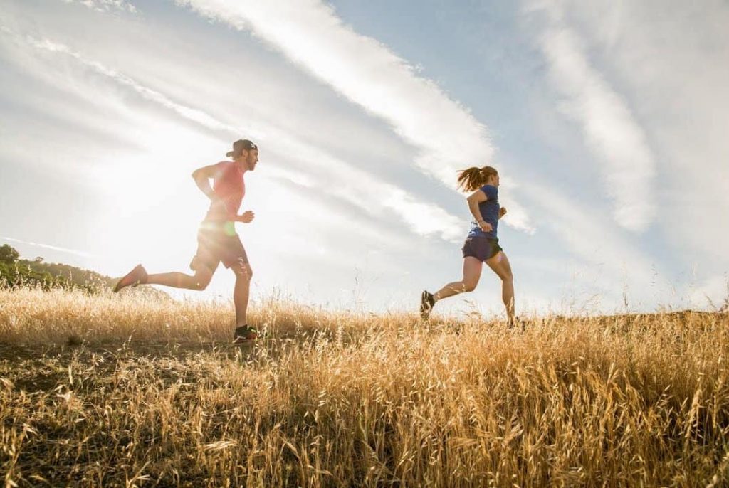 two people running across a field with good form.