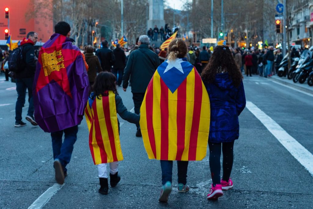 People walking streets in Catalunya wearing the Catalan flag