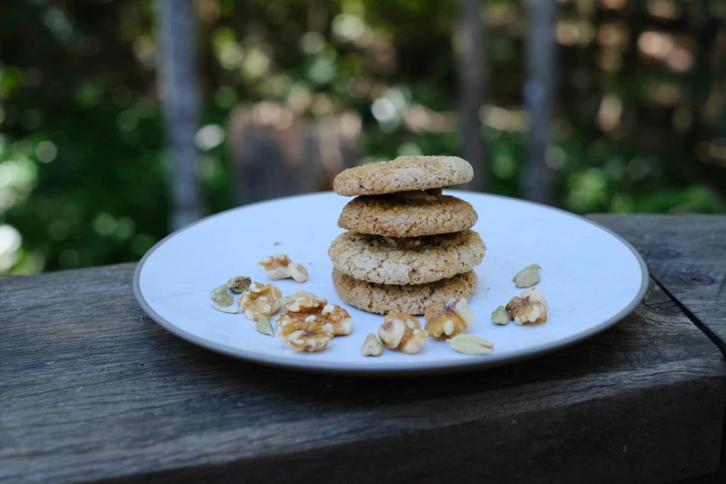 Persian walnut cookies on a plate with trees in the background